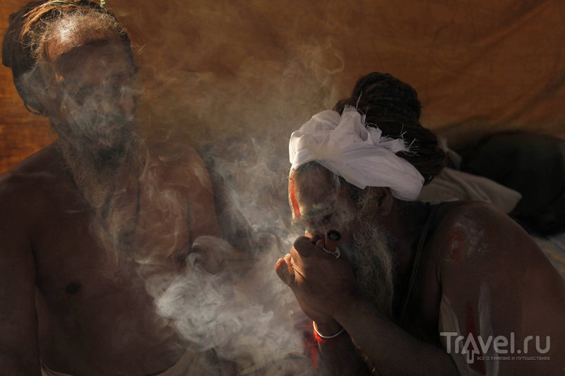 Святой человек курит марихуану в Сангам / Индия