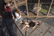 Туристы делают снимки на стеклянном полу Эйфелевой башни. 